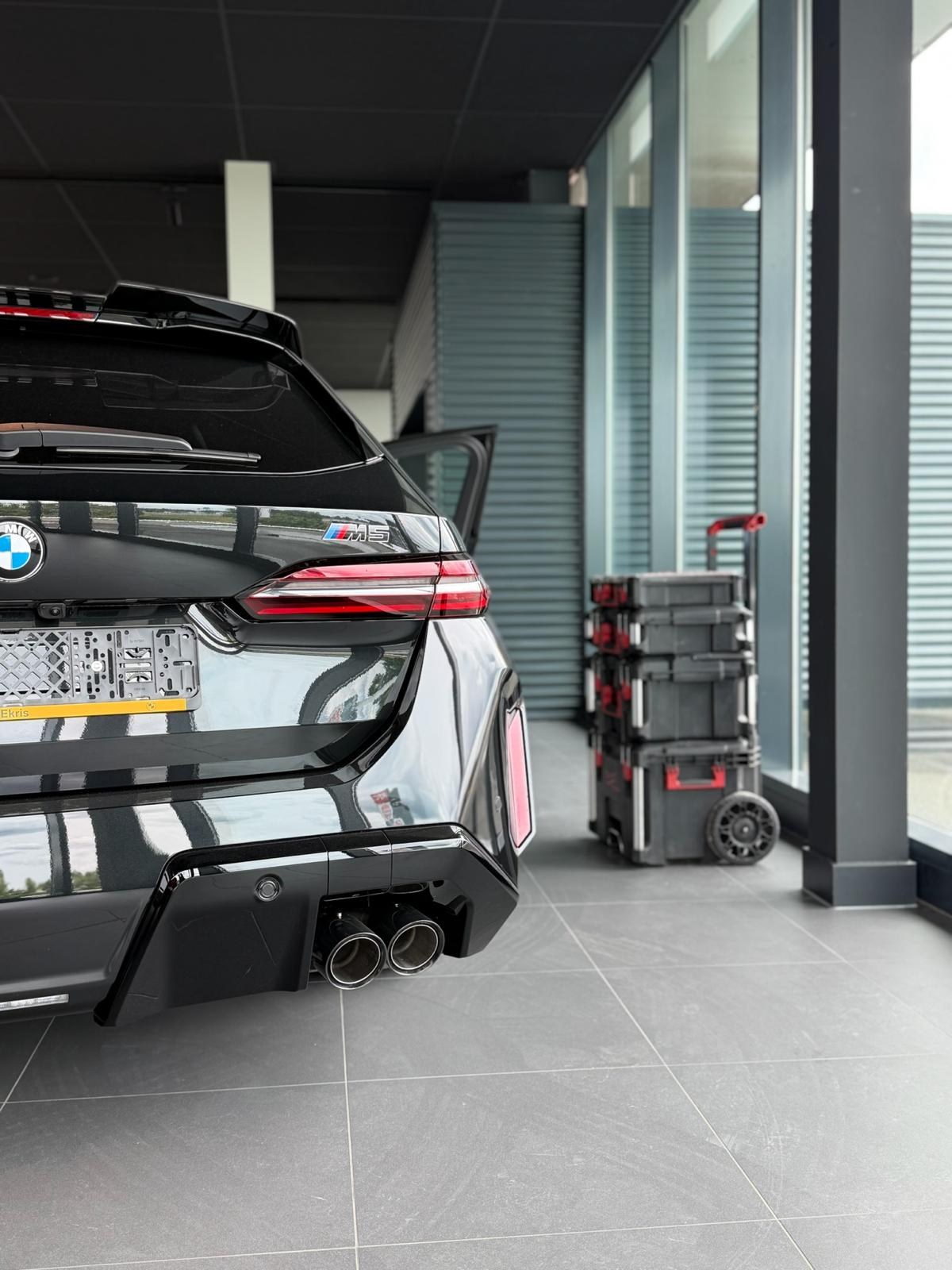 Zwarte BMW M5 in de studio van Car Studio East tijdens werkzaamheden aan het voertuig
